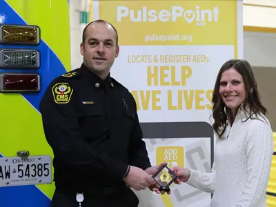 Chief Justin Lammers presents Tecumseh resident Andrea Ducharme with an Essex-Windsor EMS meritorious service coin.