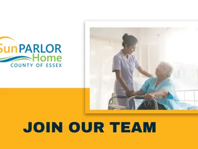 A personal support worker smiles at a resident with a walker