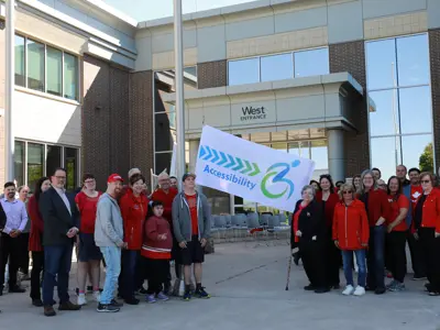 County of Essex employees and Accessibility Advisory Committee members and others in red shirts raise an Accessibility flag at the County of Essex Administration Building.