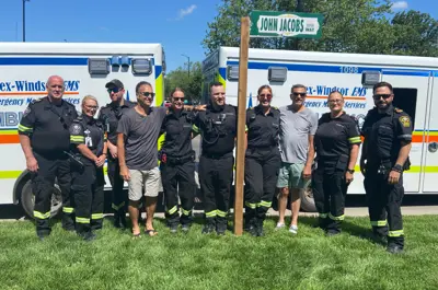 Paramedics gather at the new John Jacobs Way sign.