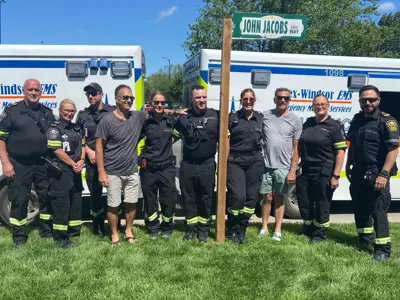 Paramedics gather at the new John Jacobs Way sign.