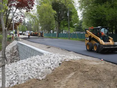  A piece of machinery smooths new asphalt on County Road 50