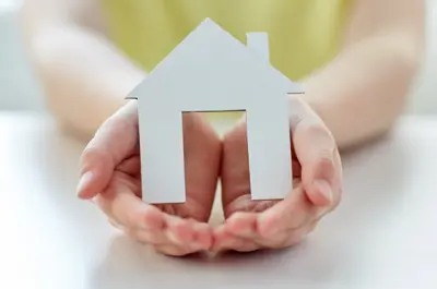 Hands cradling a cut-out of a house