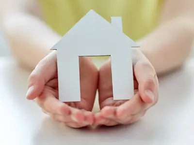 Hands cradling a cut-out of a house