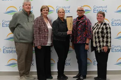 Rebecca Belanger and her team with the Project of the Year Award in front of a backdrop with County of Essex logos.