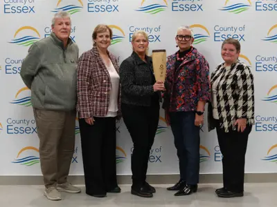 Rebecca Belanger and her team with the Project of the Year Award in front of a backdrop with County of Essex logos.