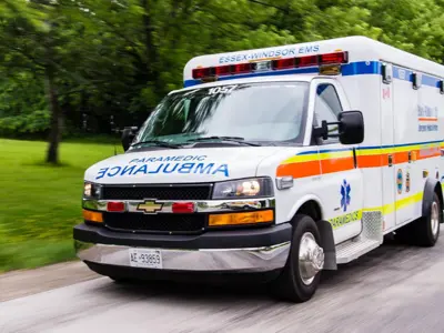 An Essex-Windsor EMS ambulance with a blurred background suggesting motion.